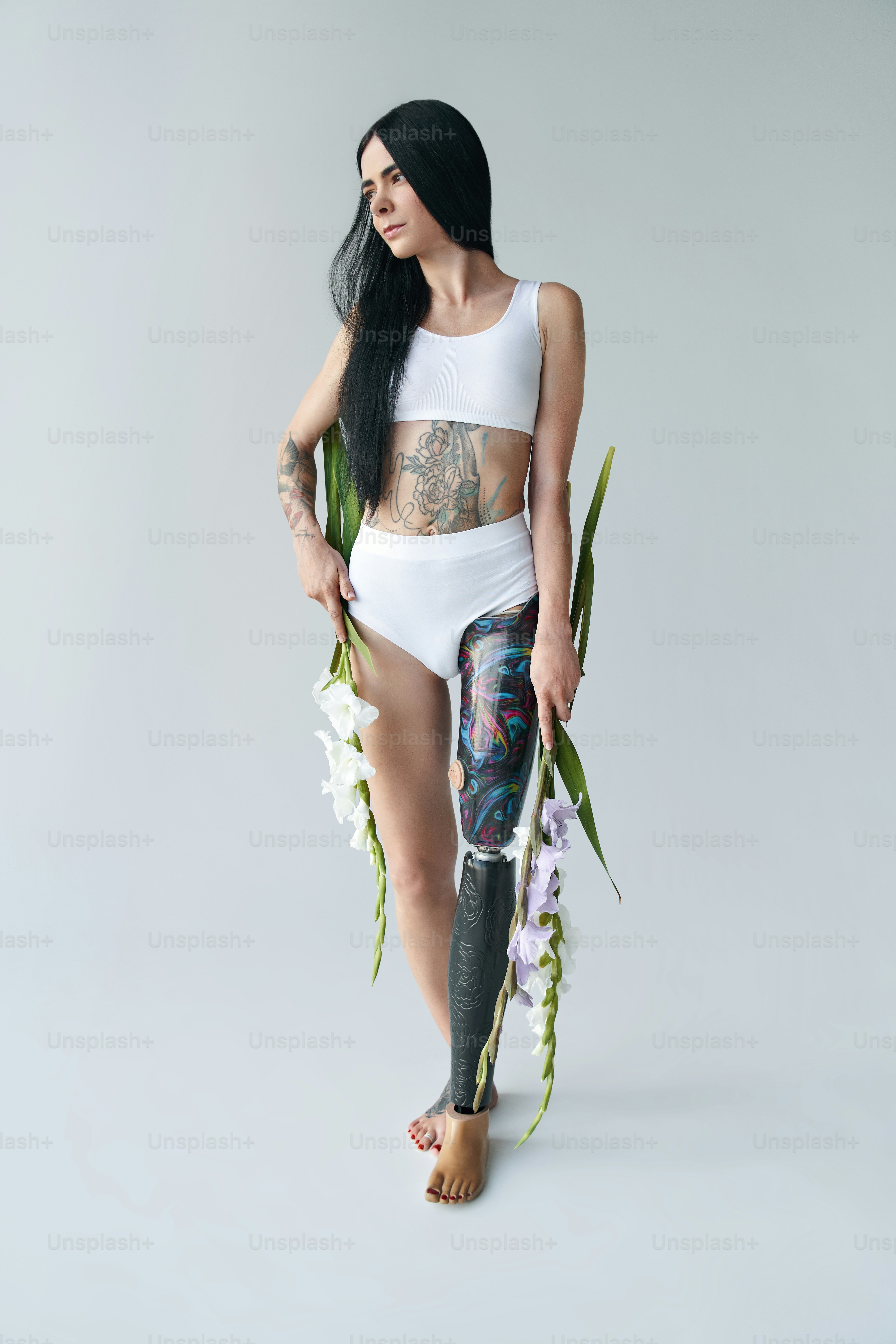 Eine Frau mit einem Prothesenbein, die weiße und violette Gladiolusblumen hält