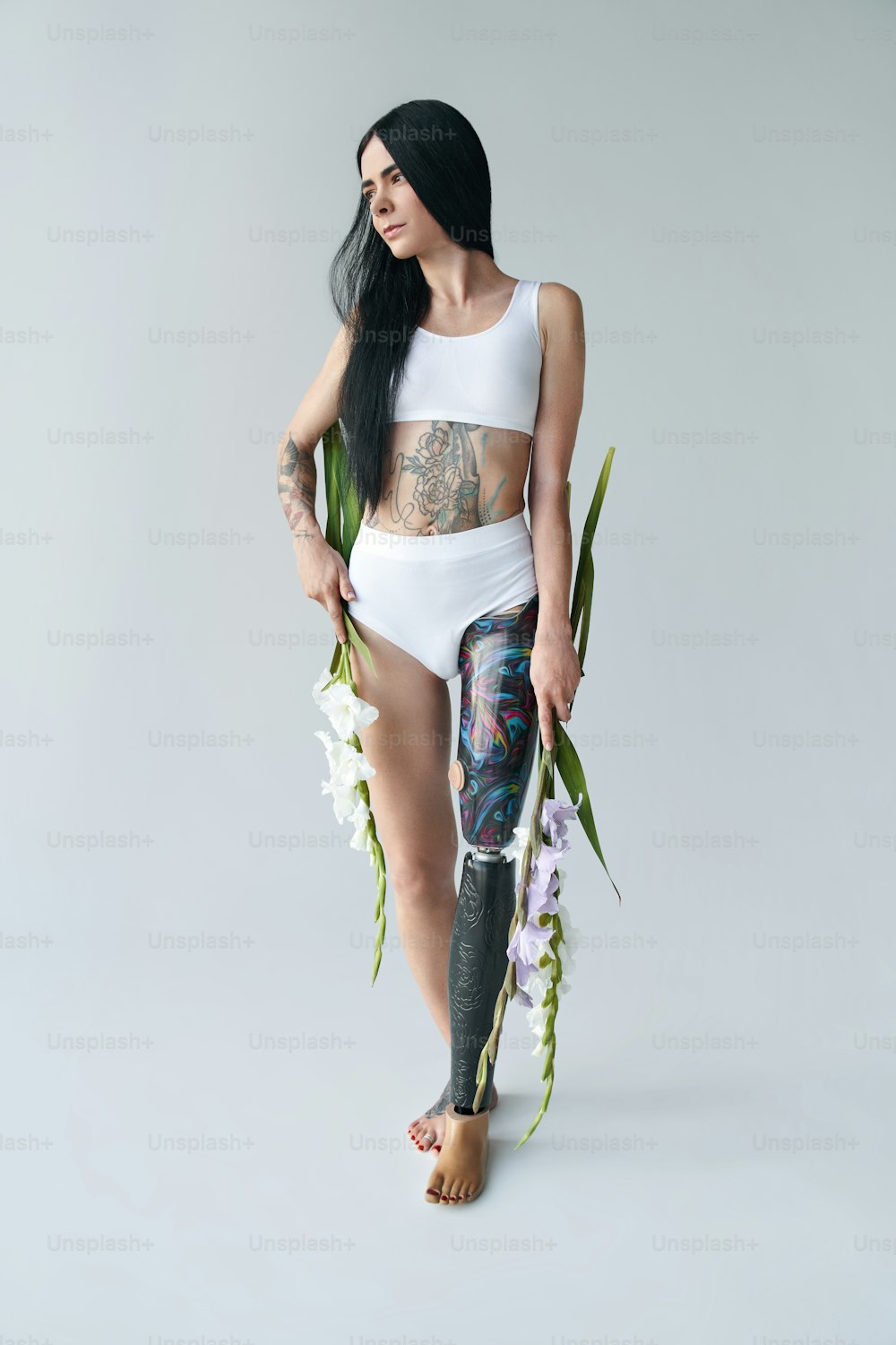 Vista vertical de una joven morena con una pierna artificial sosteniendo un ramo de flores en sus manos y posando ante la cámara. Concepto de personas con necesidades especiales