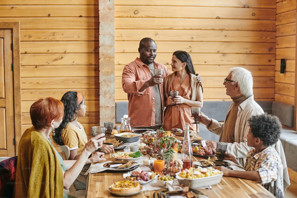 Young couple congratulating their parents, they standing and saying the toast during dinner at festive table