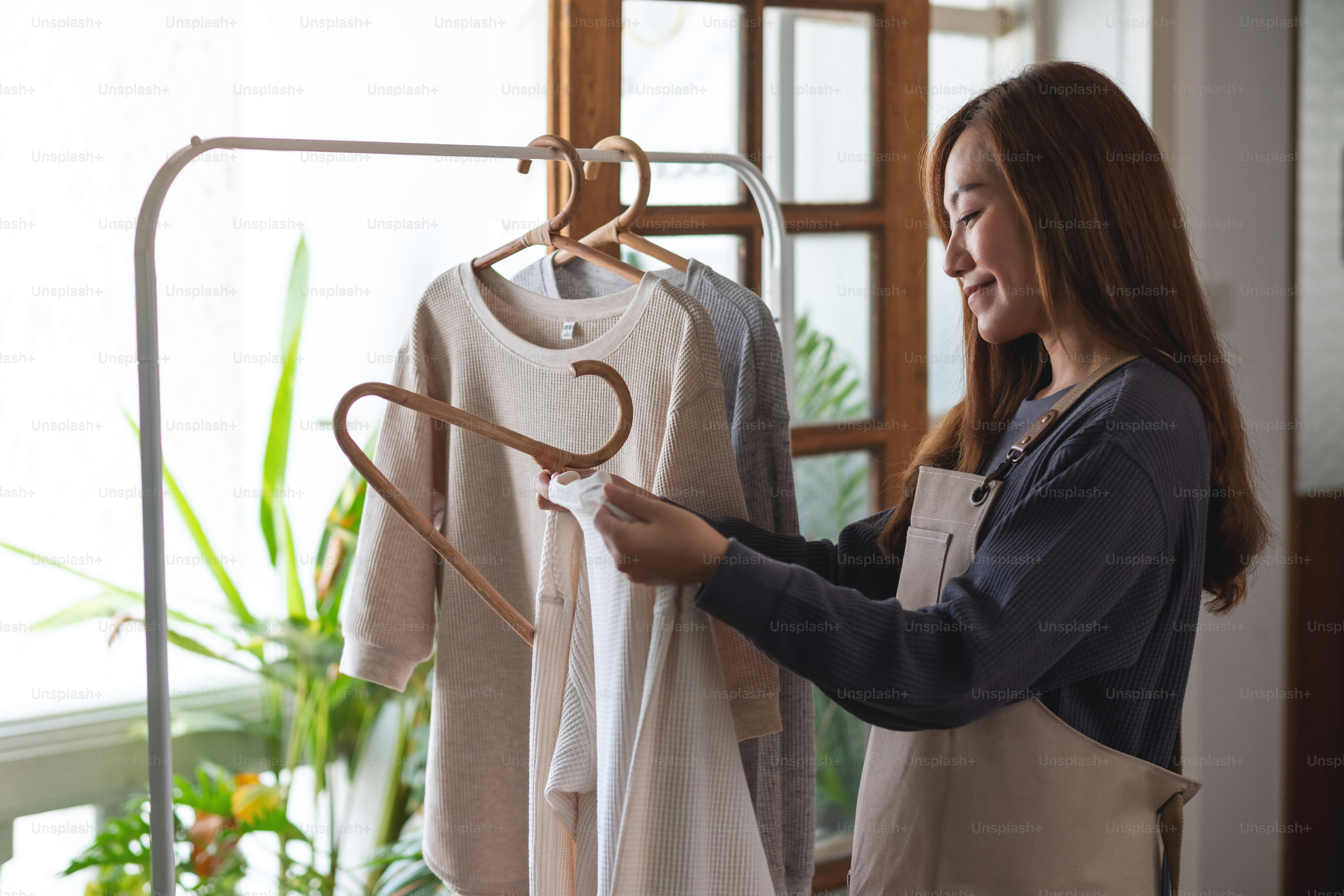 A housewife doing laundry, washing and hanging shirts on clothesline at home