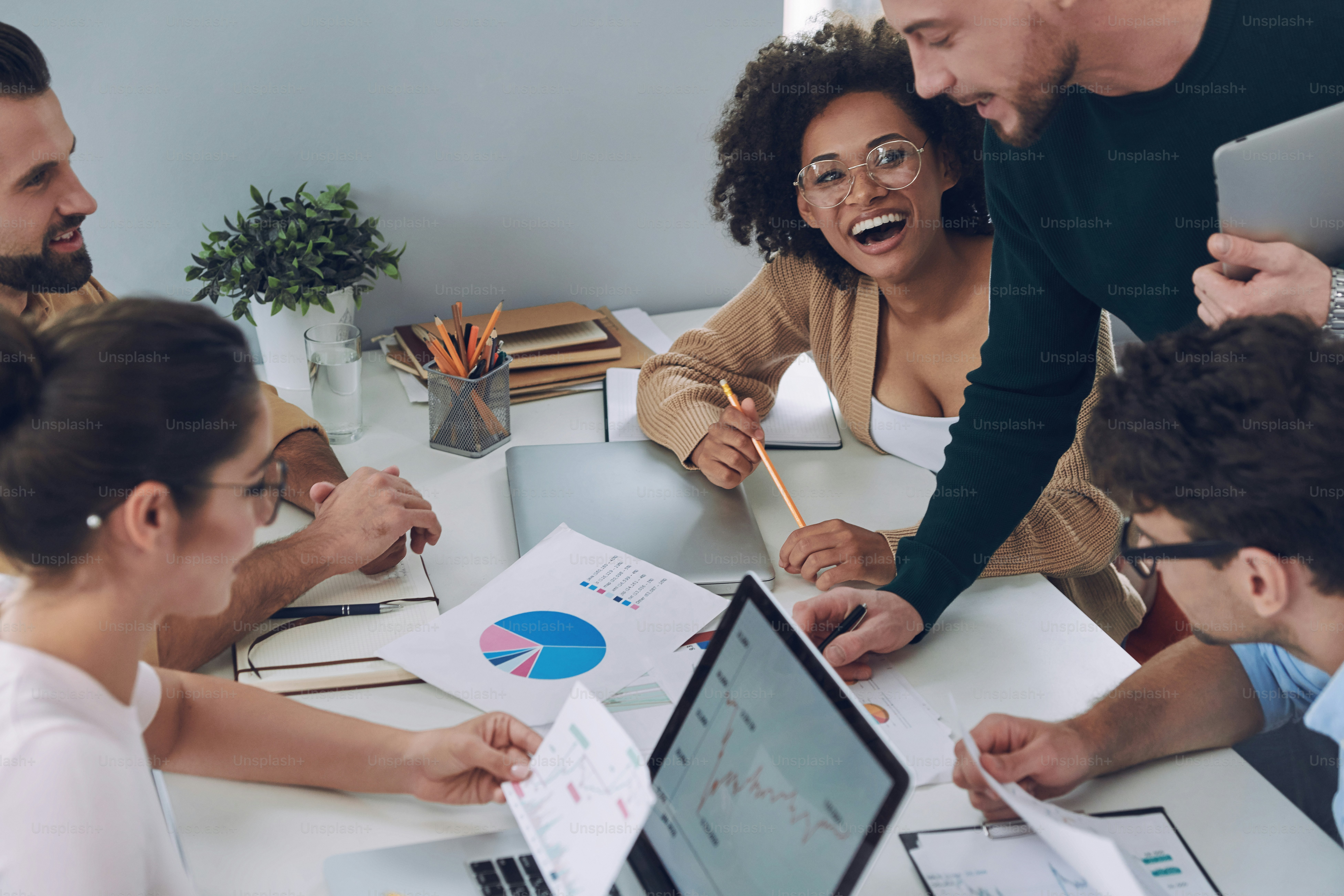 Top view of confident young people in smart casual wear discussing business while having meeting in office