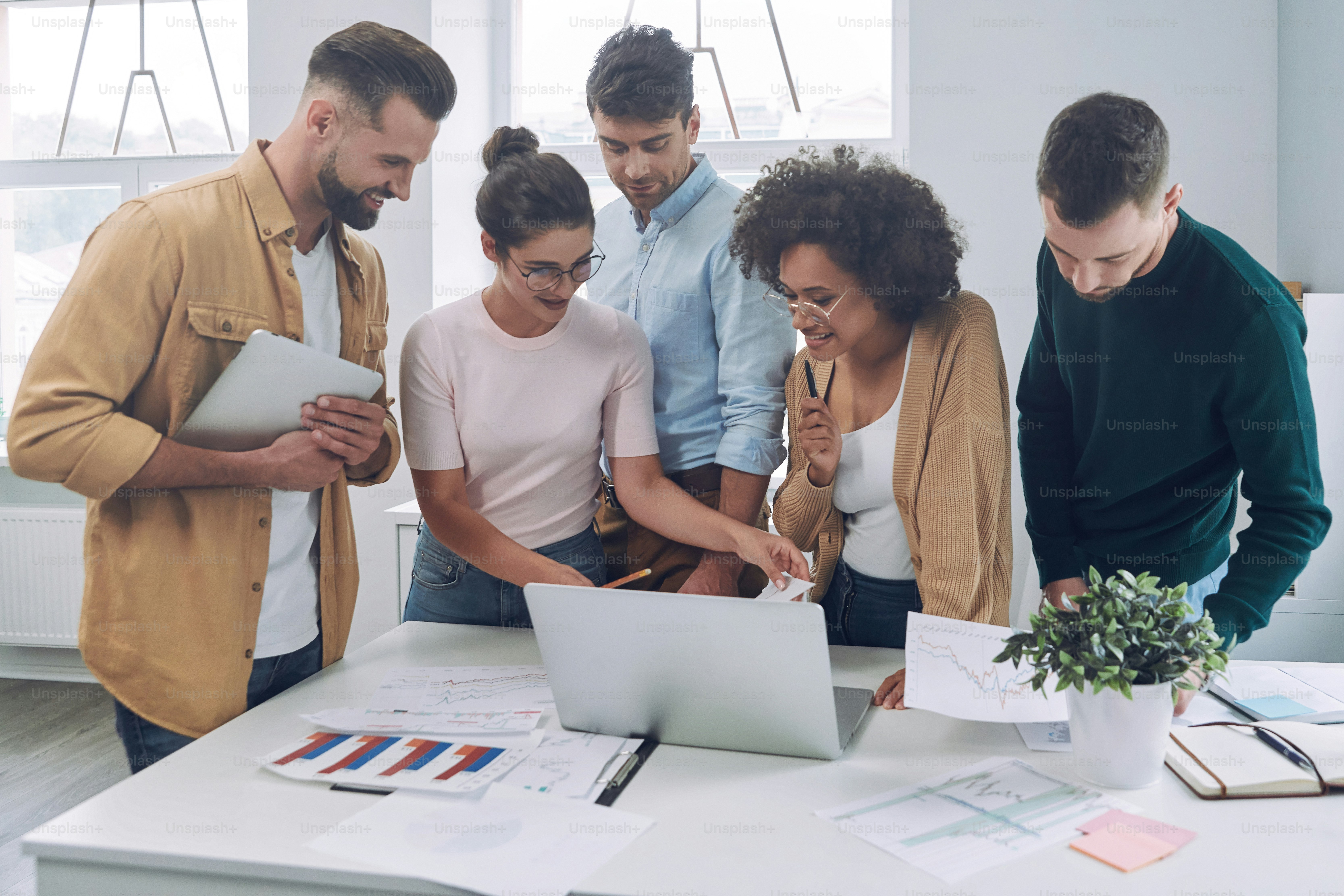 Group of confident young people in smart casual wear discussing business while having meeting in office