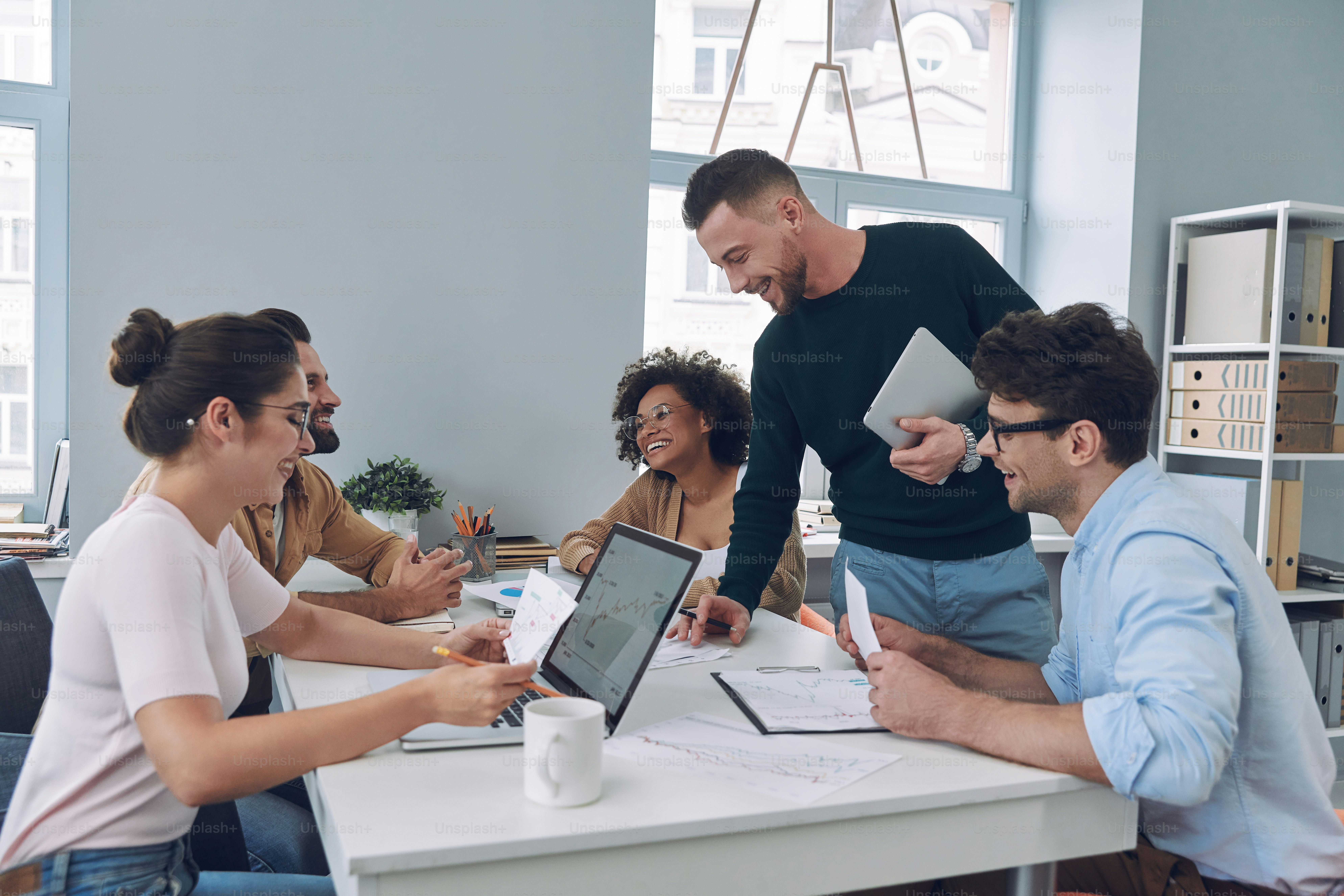 Group of confident young people in smart casual wear discussing business while having meeting in office