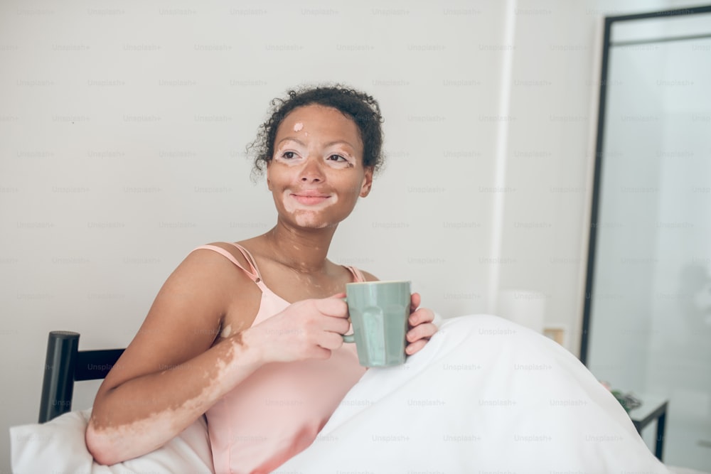 モーニングコーヒー。朝、ベッドに横たわりながらコーヒーを飲む女性