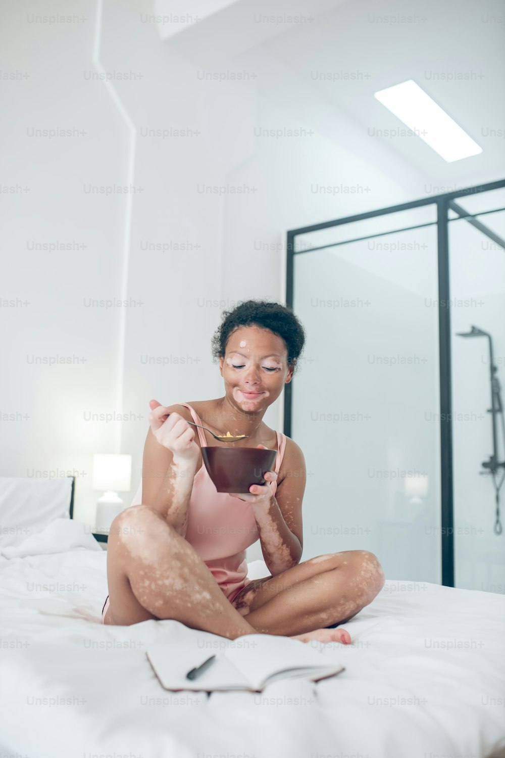 Desayuno. Una mujer sentada en la cama y desayunando