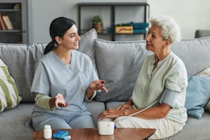 Porträt einer lächelnden älteren Frau, die mit einer Krankenschwester im Altersheim spricht