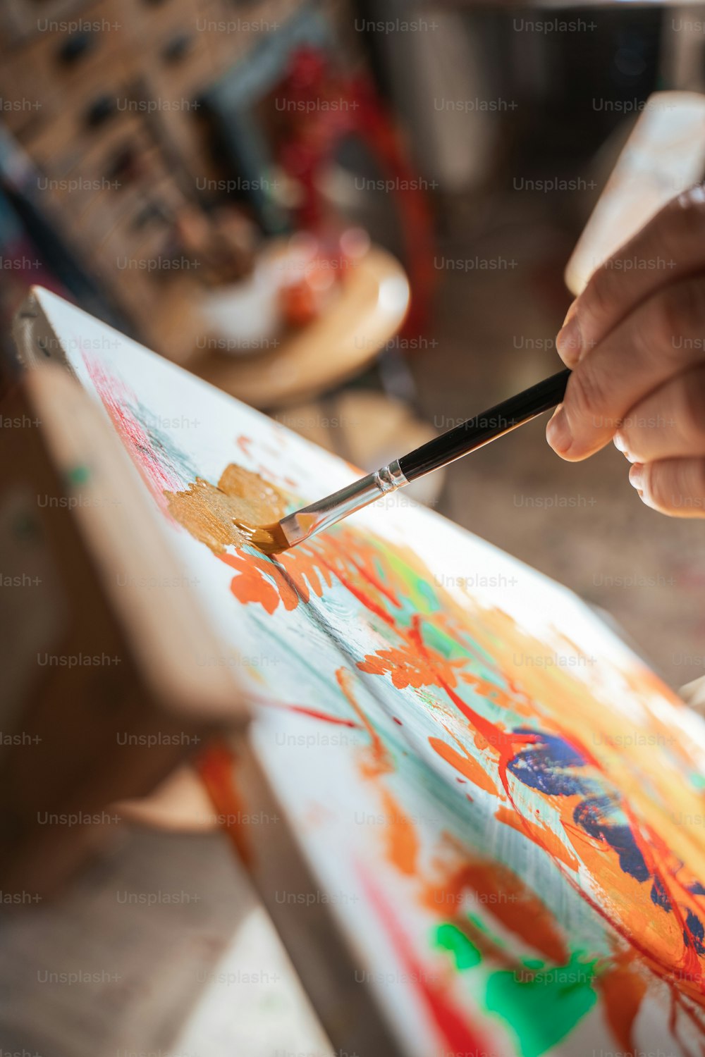 Close up view of the unrecognizable woman holding brush and mixing paints on the canvas while drawing at her home studio. Stock photo