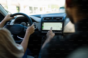 Close up of a young couple looking at the digital map on the GPS map of their car