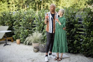 Multiracial couple drinking cocktails at home garden. European girl and black man spending time together. Concept of leisure and relationship. Modern domestic lifestyle. Enjoying people