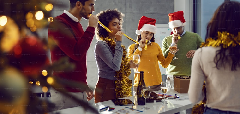 Capodanno e festa di Natale. Un piccolo gruppo di amici multiculturali in piedi in ufficio e divertendosi a Capodanno.