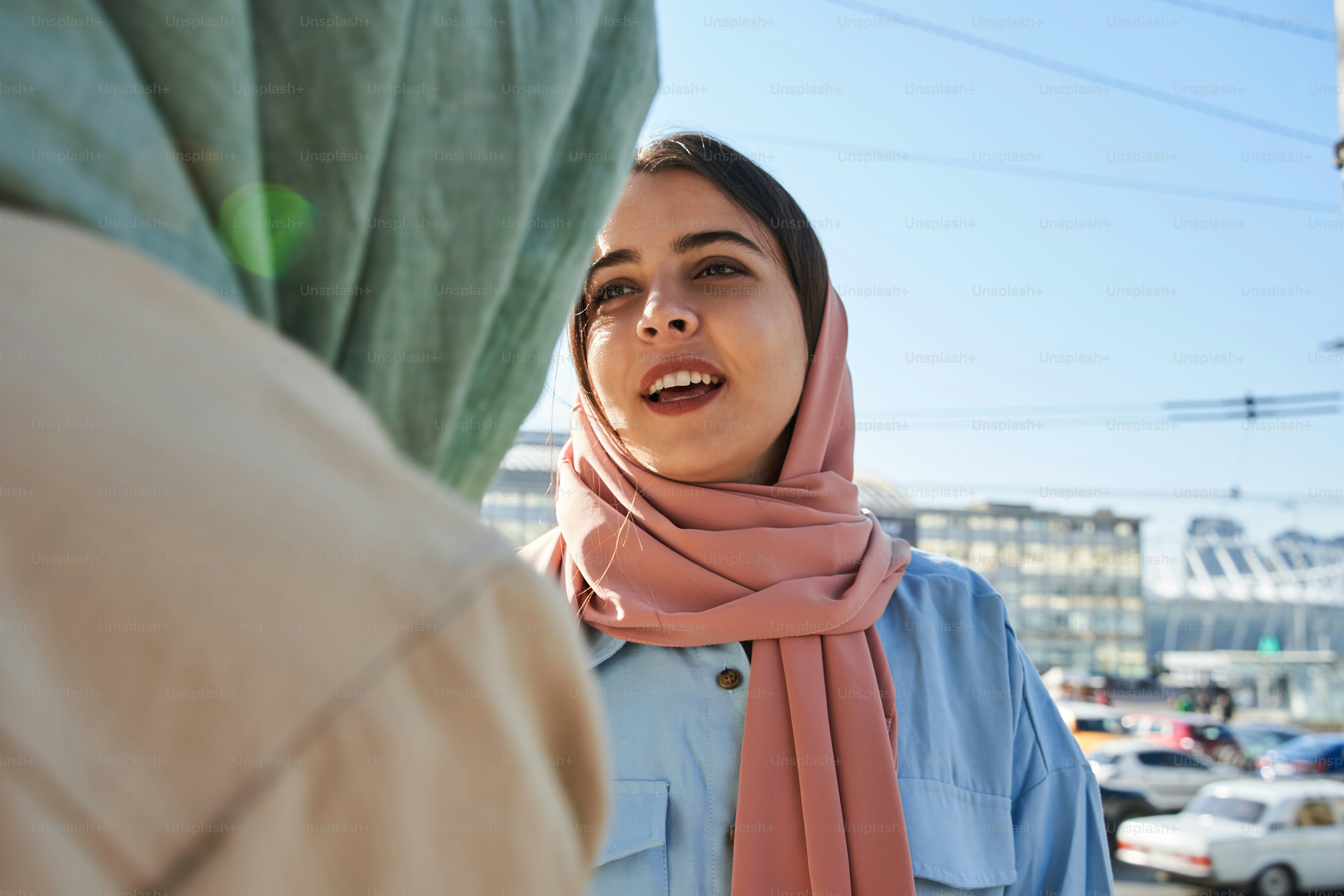 O que você acha. Vista retrato da simpática menina árabe usando hijab conversando com sua melhor amiga enquanto caminha na cidade