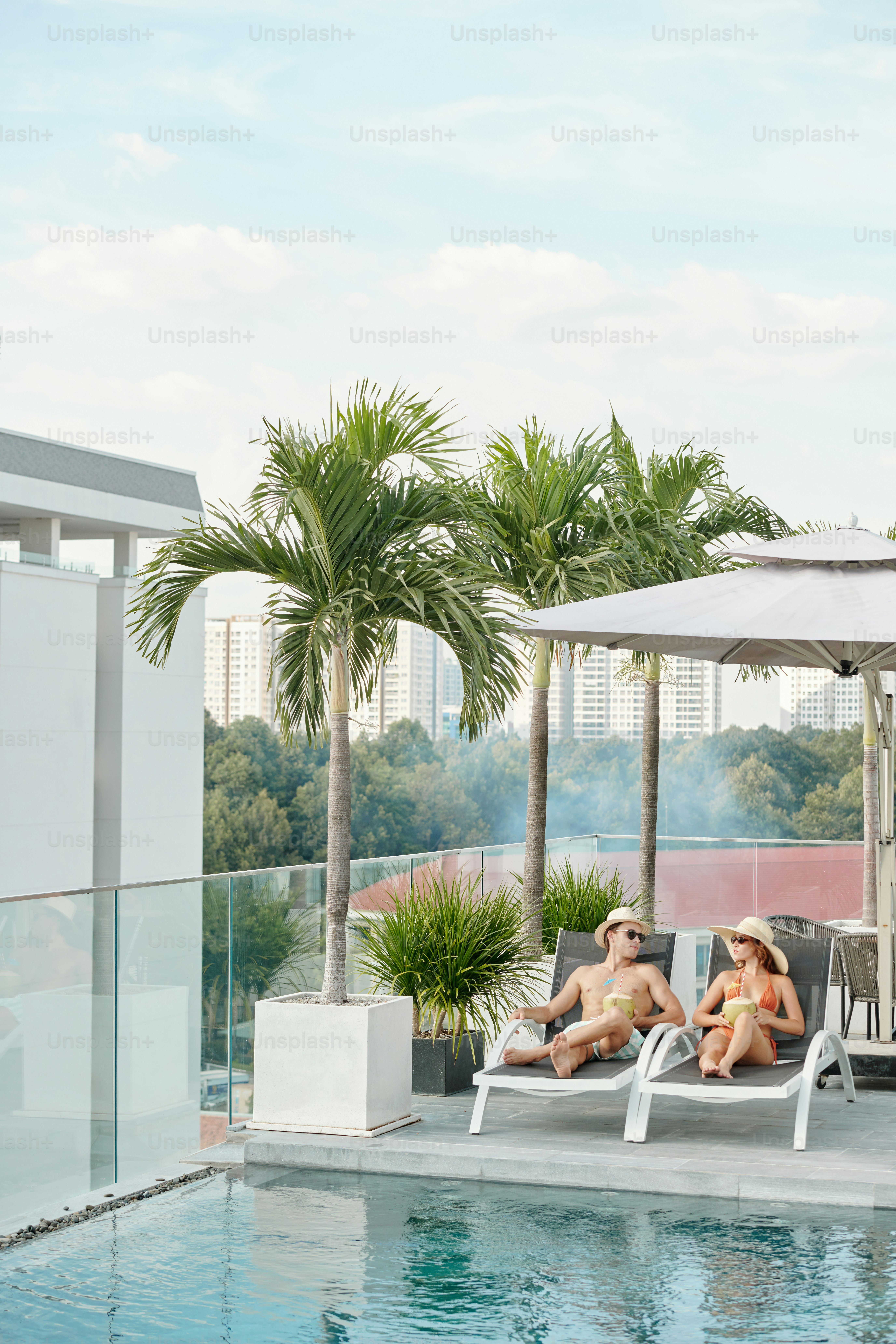 Young couple spending honeymoon at swimming pool on rooftop of hotel ...