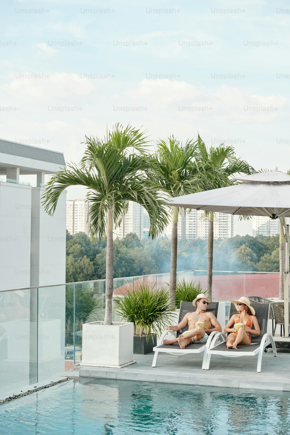 Young couple spending honeymoon at swimming pool on rooftop of hotel building