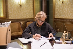 Avvocato donna seria che esamina i documenti mentre controlla le informazioni prima di firmare e timbrare i documenti