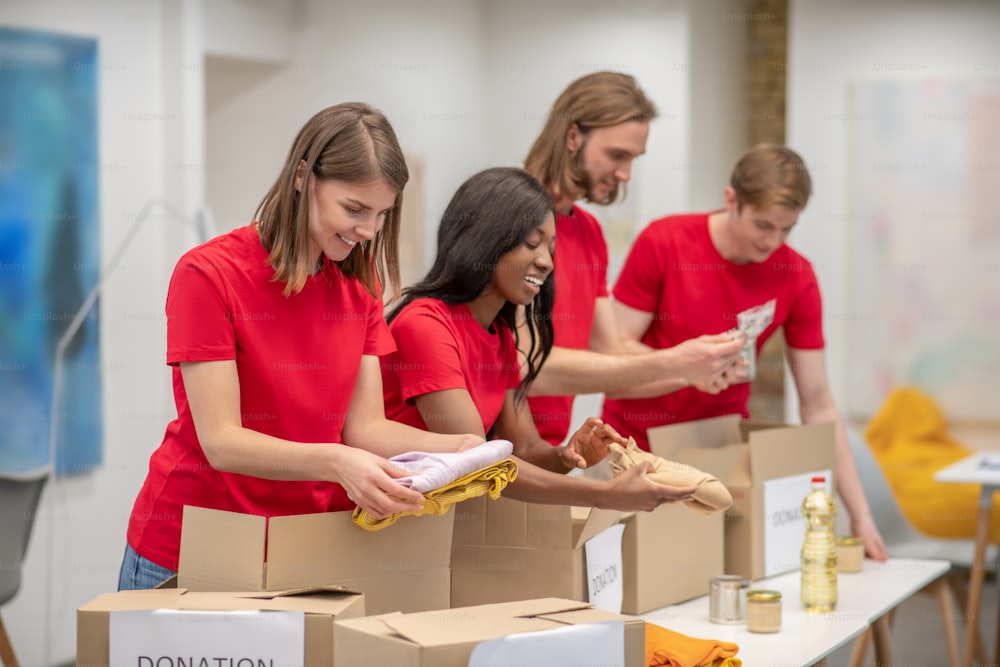 Humanitarian help. Young peeple in red packing the cardboards with humanitarian help