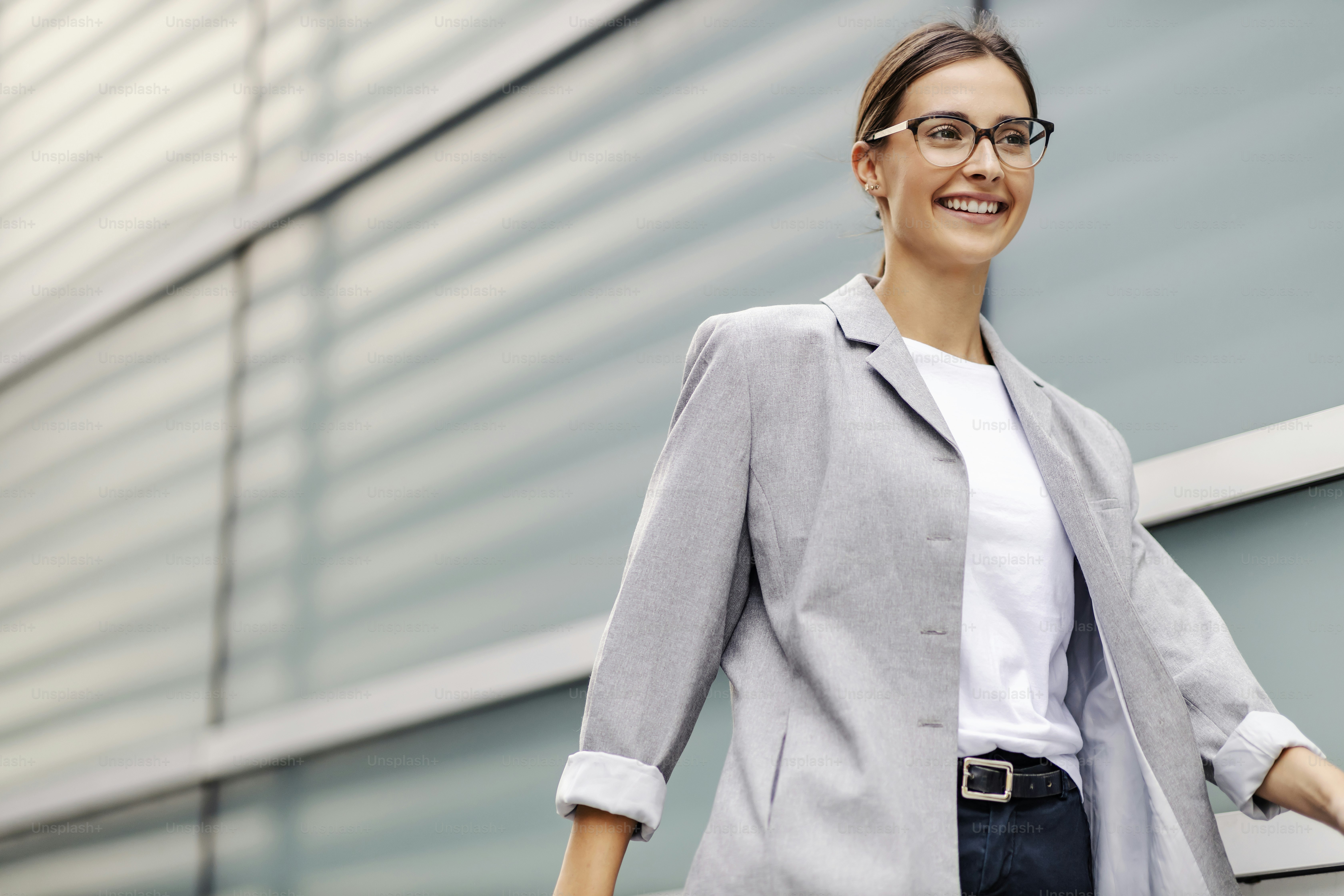 A smiling young businesswoman dressed elegantly walking on the street. A busy woman going to work with a smile on her face. A businesswoman walking