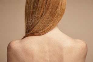 Vista trasera mínima de una mujer pelirroja pecosa con hombros desnudos, espacio de copia