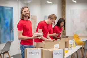 Humanitarian help. Young peeple in red packing the cardboards with humanitarian help