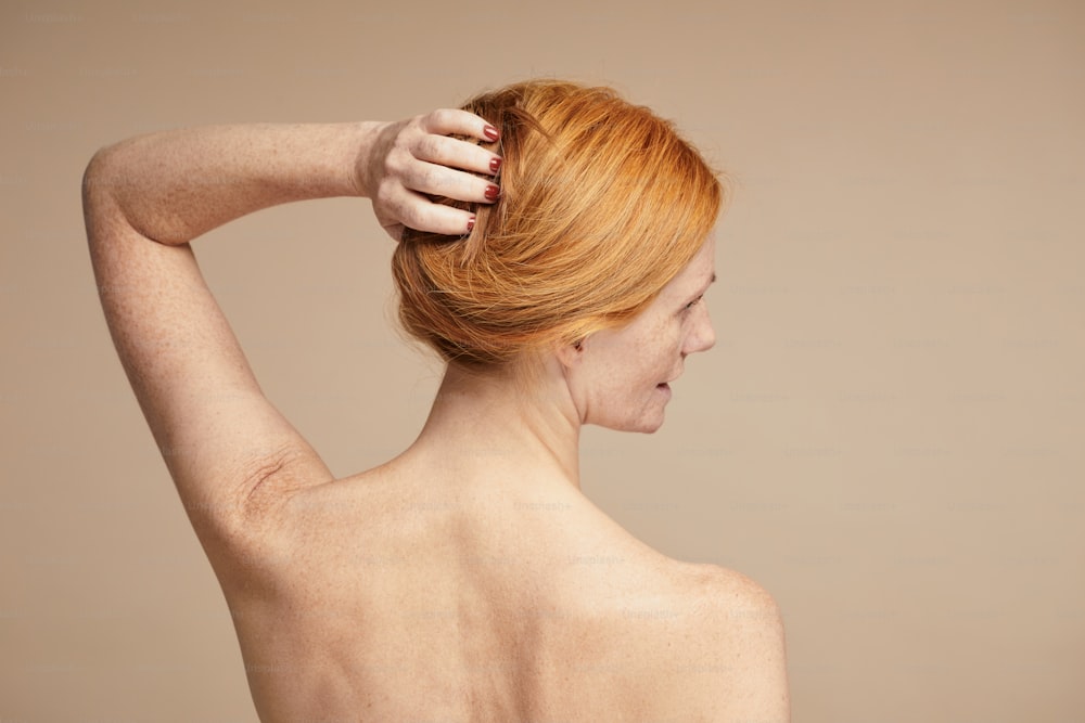 Minimal portrait of young red haired woman with nude shoulders, copy space