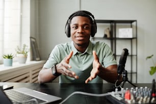 Porträt eines afroamerikanischen Mannes, der während der Aufnahme eines Podcasts im Studio in die Kamera spricht