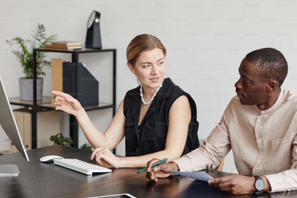 Portrait of female manager talking to partner while discussing project at desk in office