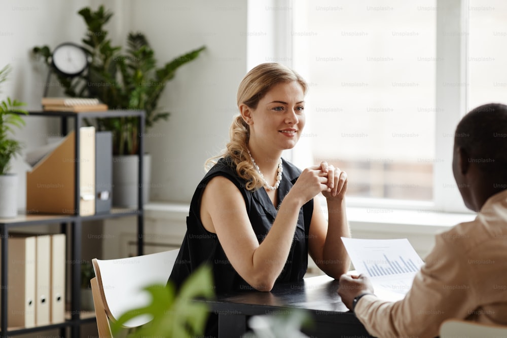 Portrait of successful businesswoman talking to employee in office and smiling, copy space