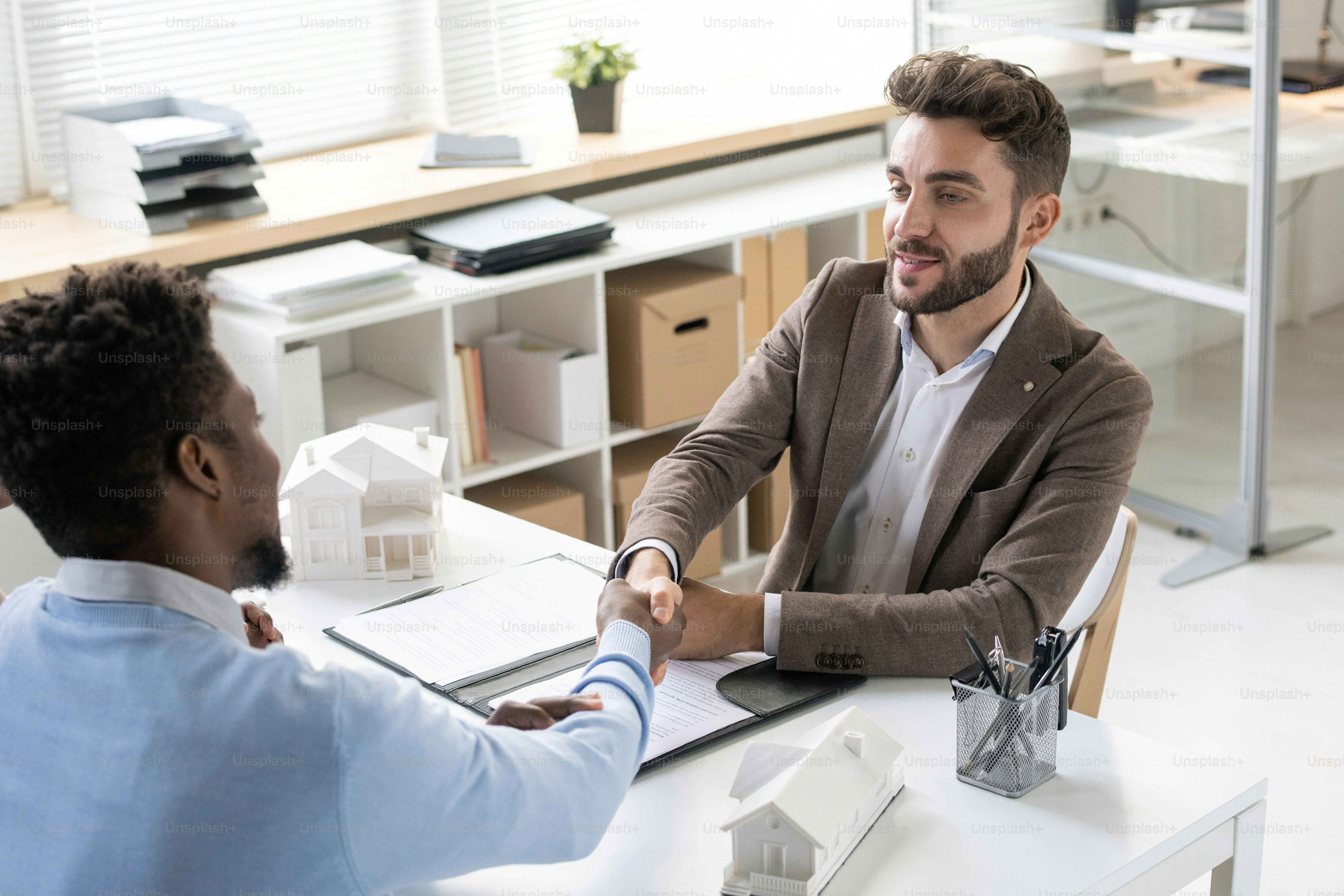 Rental agent of bank specialist making handshake with customer who taking out house loan