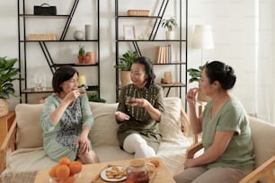 Gruppo di amiche senior che si incontrano a casa per bere il tè con i biscotti e discutere di notizie
