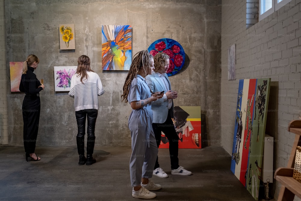 Varias visitantes femeninas de la galería de arte contemporáneo mirando obras de arte creativas de artistas modernos