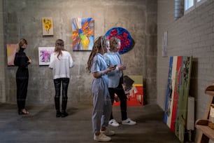 Several female visitors of contemporary art gallery looking at creative artworks of modern artists