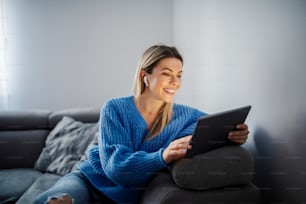 Una donna felice che ha videochiamata su tablet nella sua accogliente casa.