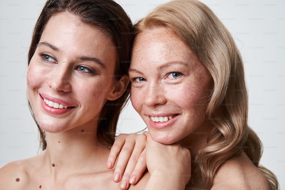 Gesundheits- und Schönheitskonzept für junge schöne Frauen. Extrem nahe Aufnahme der beiden Mädchen mit unterschiedlichem Hautzustand, die in die Kamera lächeln