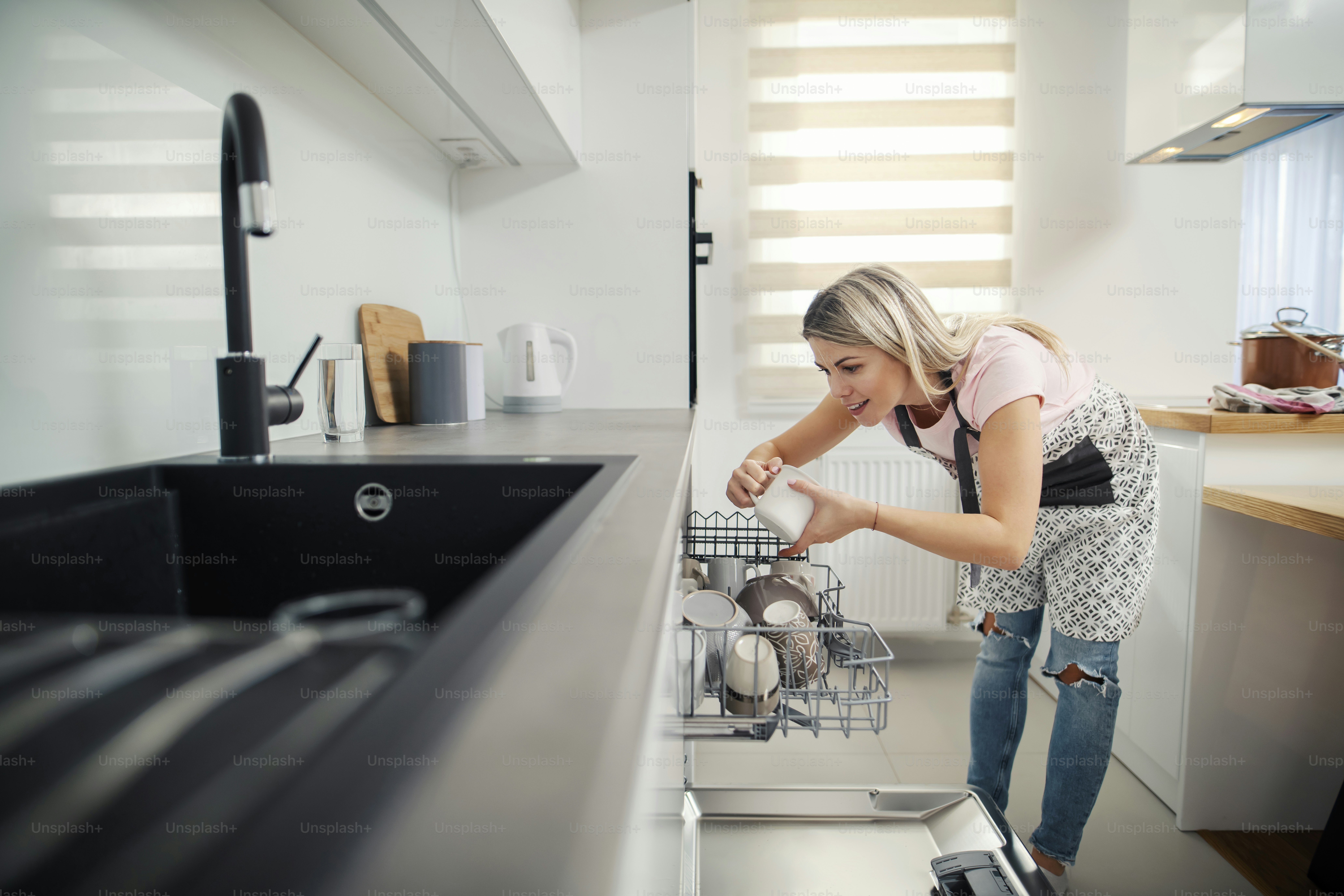 A tidy woman putting dishes into a dishwasher in her kitchen. photo