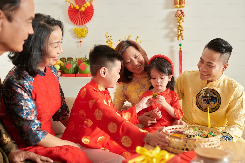 Little boy giving candied kiwi slice to little sister at Chinese New Year celebration