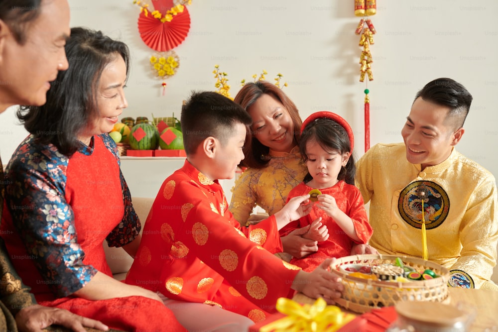 中国の旧正月のお祝いで妹に砂糖漬けのキウイスライスを与える小さな男の子
