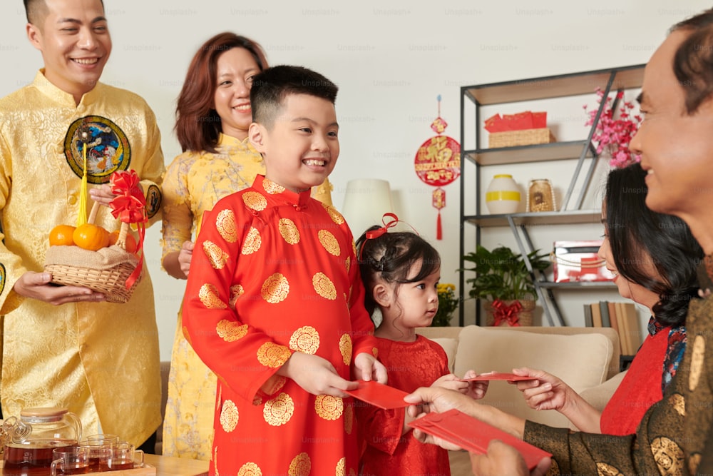 Little brother and sister accepting red envelopes from their grandparents