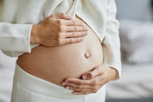 Close-up of young pregnant woman touching her belly and caring about her health