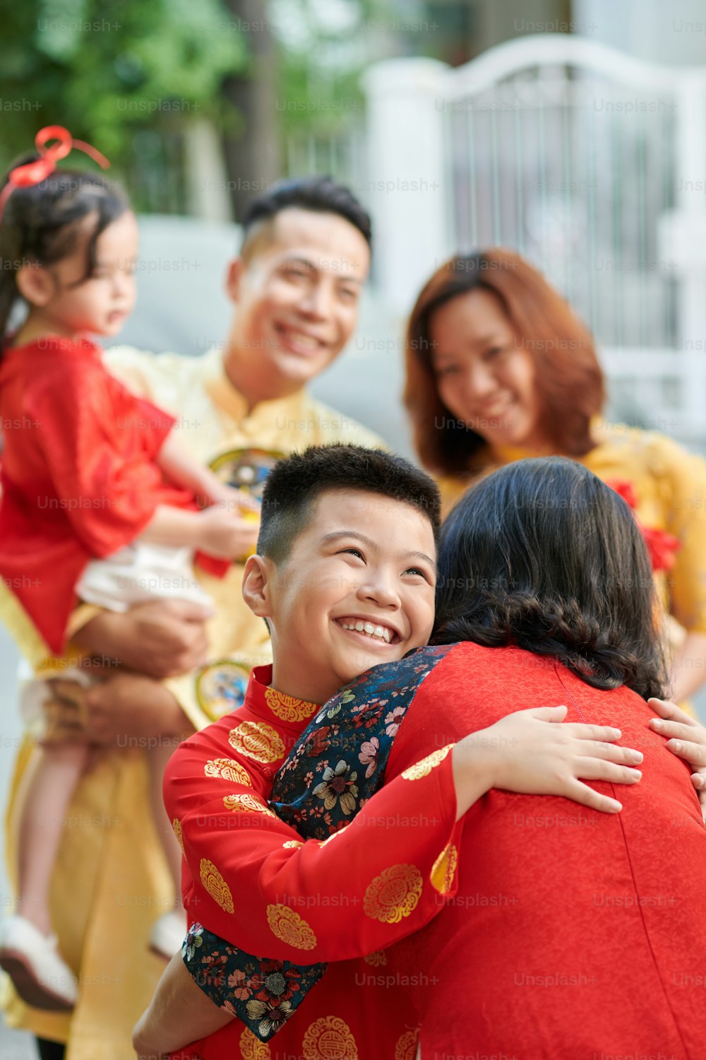 Sorrindo feliz menino pré-adolescente abraçando a avó ele e sua família visitam para a celebração do Ano Novo Lunar