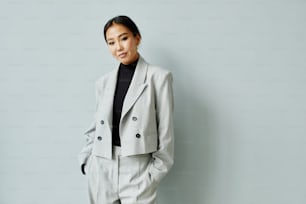 Waist up portrait of beautiful Asian businesswoman wearing suit and looking at camera, copy space