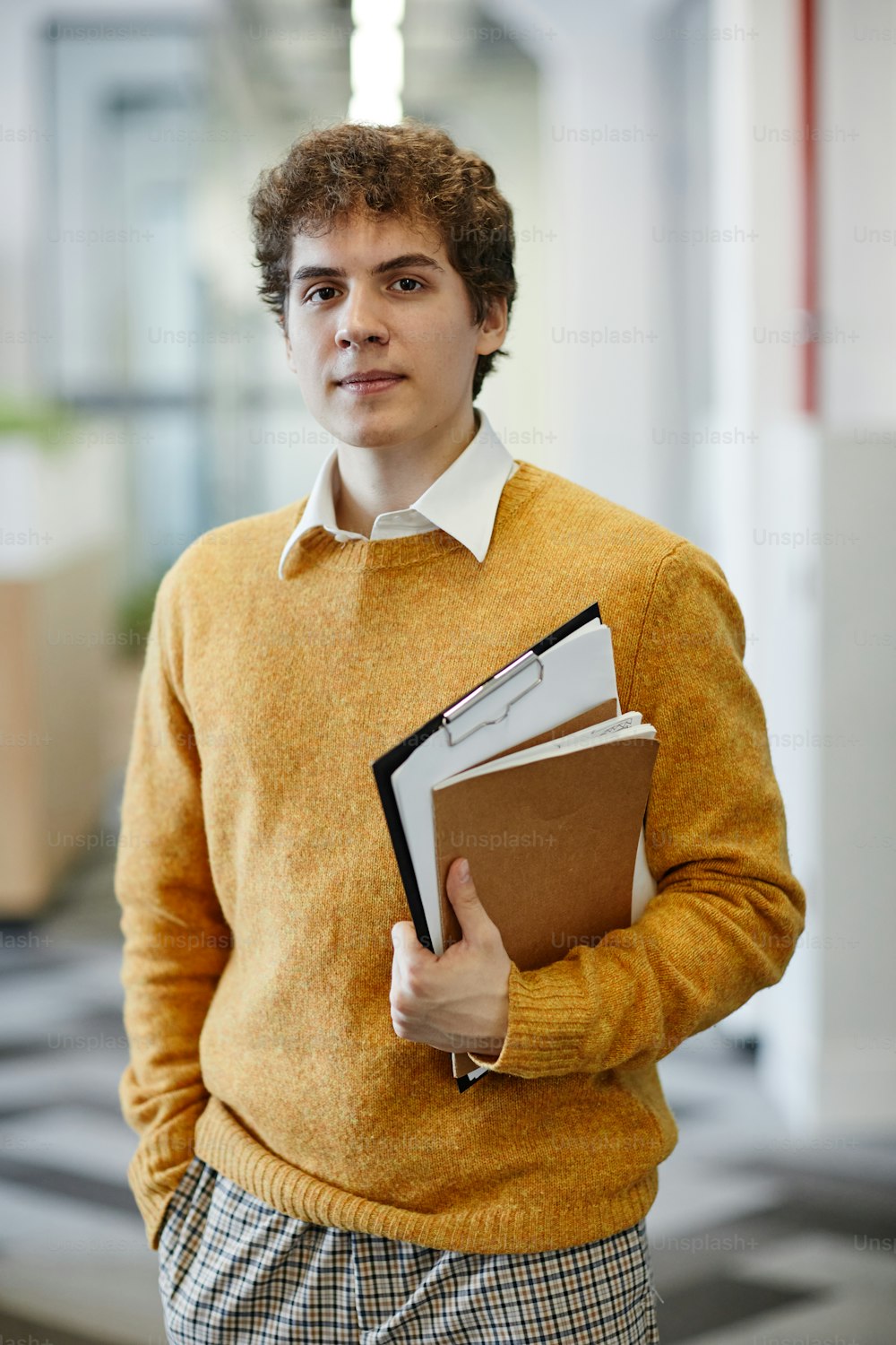 Vertical waist up portrait of young man in office looking at camera, new employee and internship concept