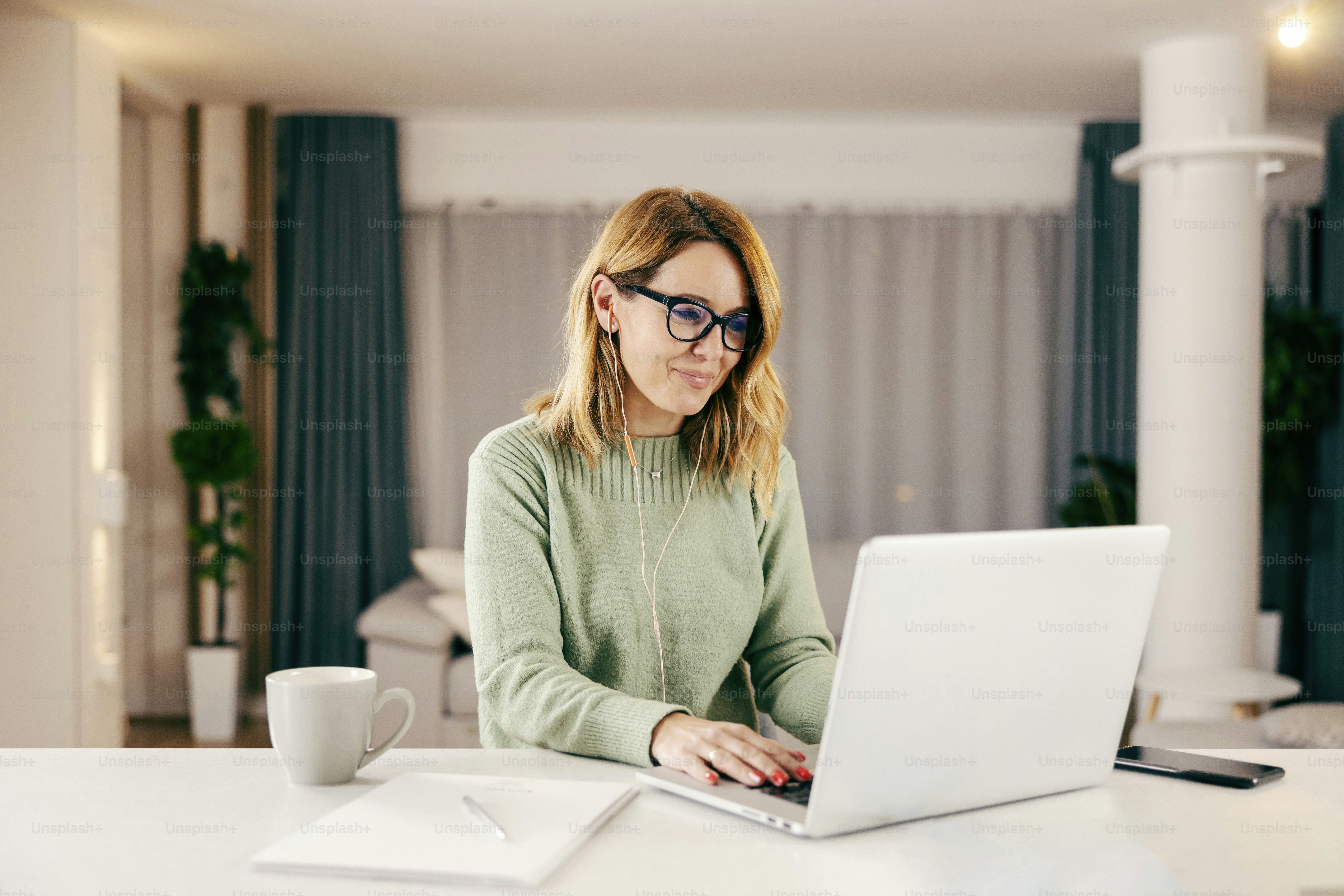 A happy woman typing on laptop and working online from home.