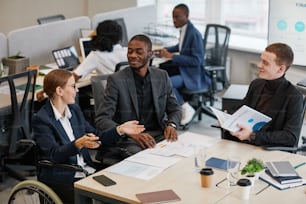 Seitenansichtsporträt eines jungen afroamerikanischen Geschäftsmannes, der im Rollstuhl sitzt, während er im Büro arbeitet, Kopierraum