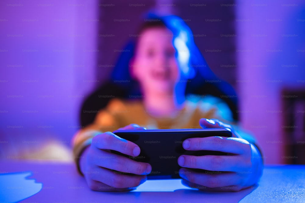 Niño jugando videojuegos en un teléfono inteligente por la noche en casa