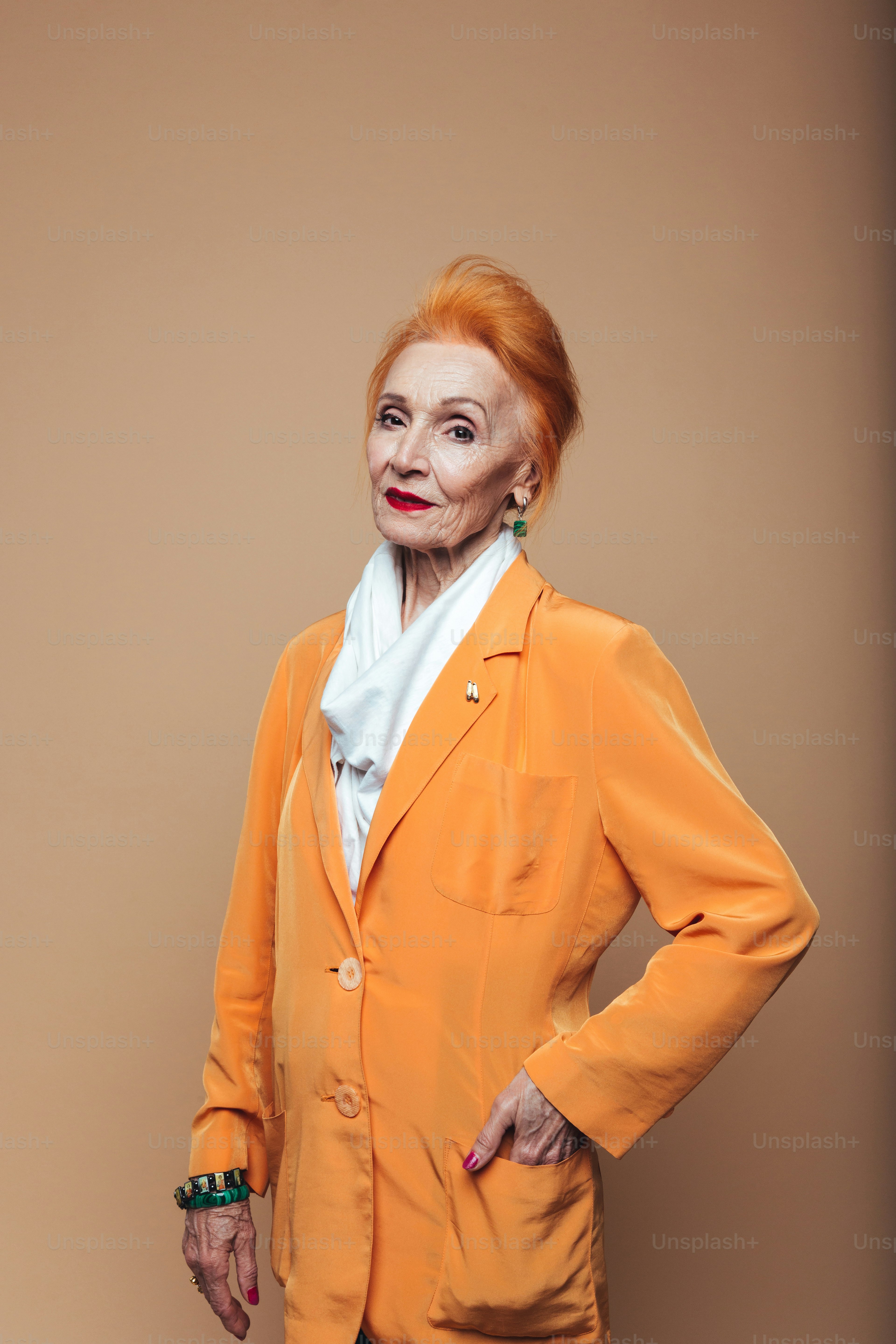 Picture of amazing mature redhead fashion woman standing isolated at studio and posing. Looking at camera.