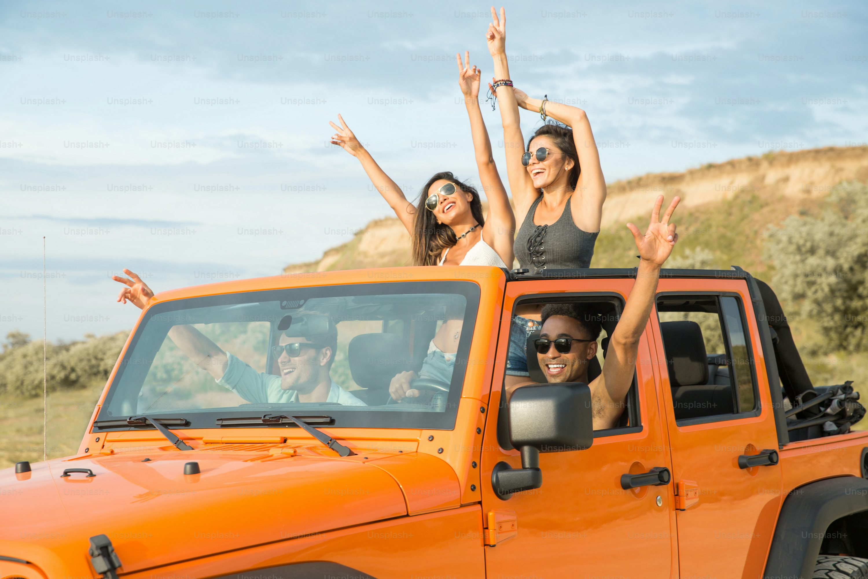 Group of happy multiethnic friends having fun by travelling together by a car