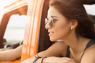 Primer plano de una mujer sonriente feliz sentada y mirando por la ventana en un automóvil