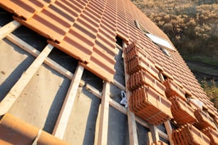 Pilas de tejas de cerámica amarilla para cubrir el techo de un edificio residencial en construcción.