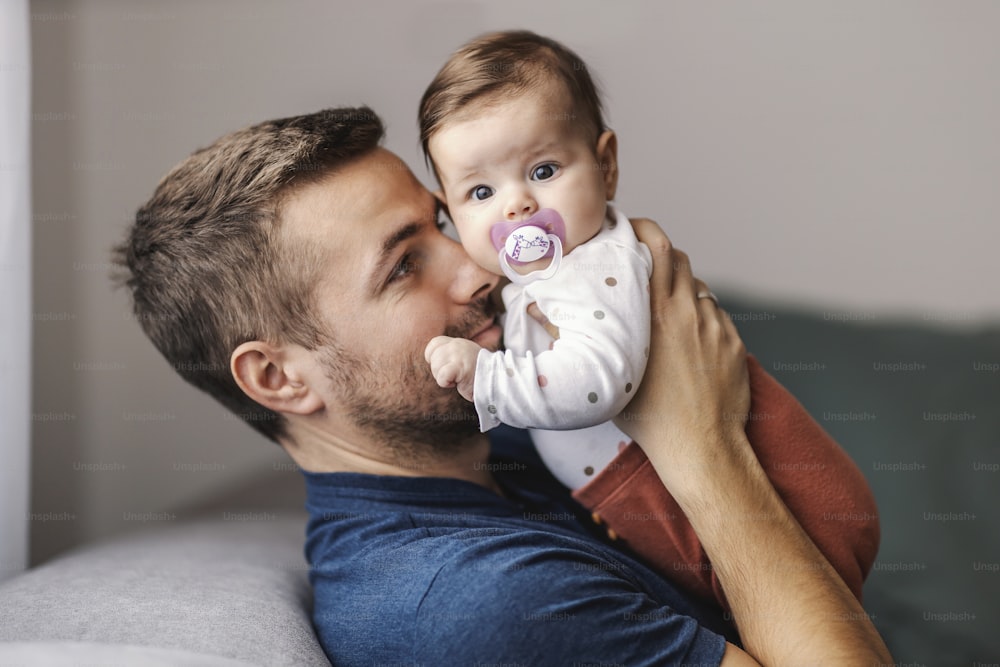 A young father snuggling with daughter at home.