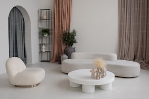 Interior of spacious living room with white comfortable couch, armchair and round table with group of handmade vases