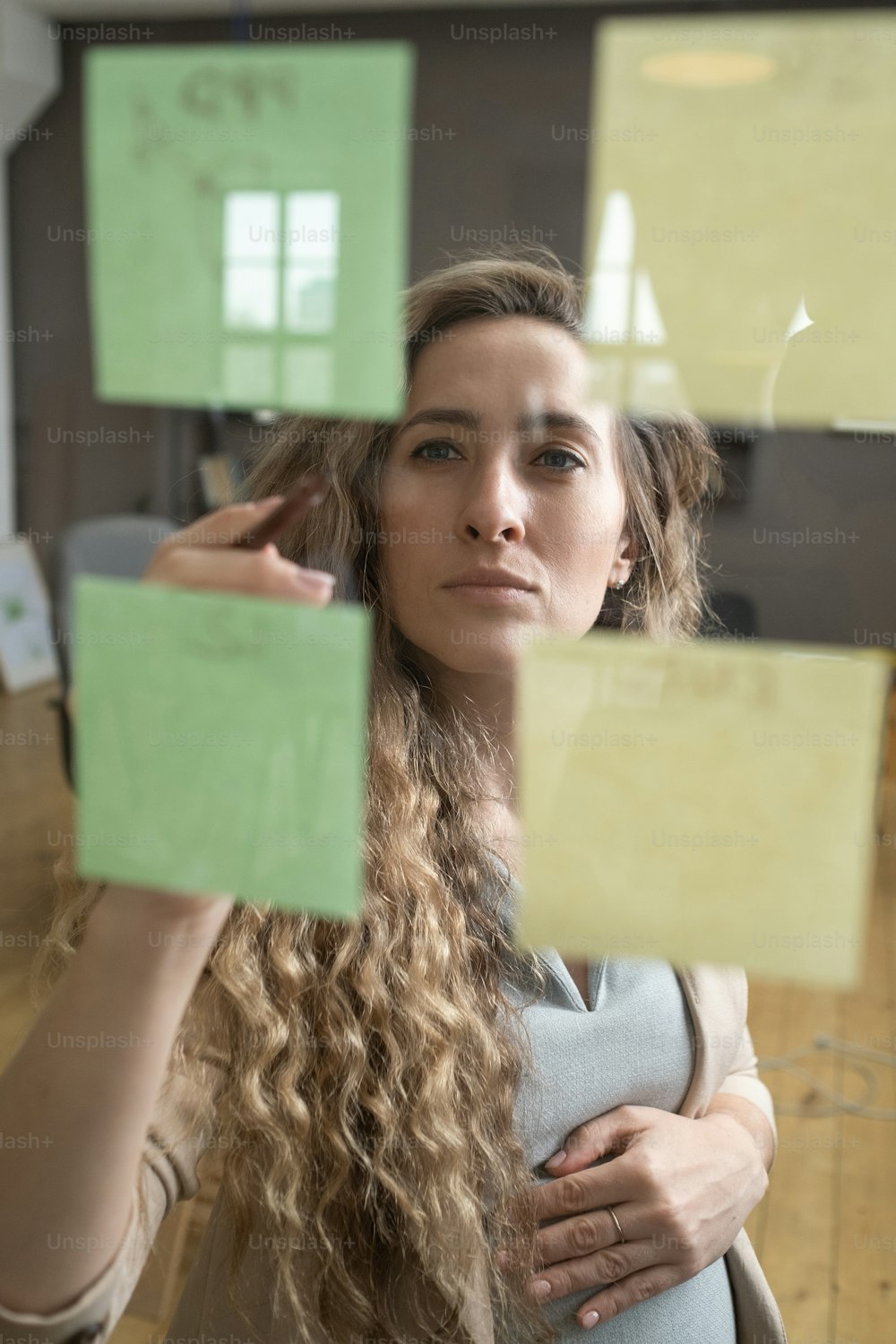 사무실에서 일을 계획하는 동안 유리벽에 메모를 읽는 젊은 임산부
